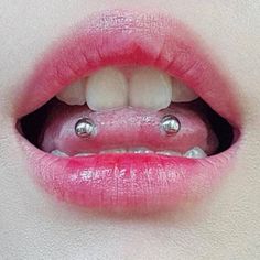 a woman's mouth with metal balls in the shape of an eye and tongue