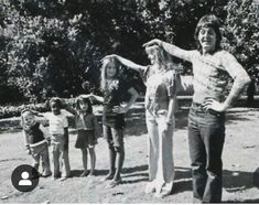 an old black and white photo of people standing in front of trees