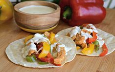 two tortillas with chicken, peppers and cheese on them next to a bowl of ranch dressing