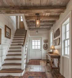 an entry way with stairs and pictures on the wall, along with a rug that matches the hardwood flooring