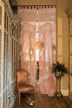 an old chair sitting in front of a pink curtain