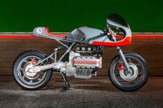 a red and silver motorcycle parked in front of a green wall