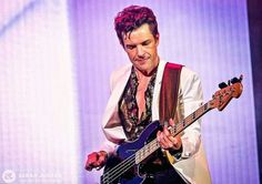 a man in white jacket playing guitar on stage