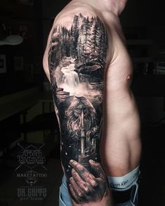 a man's arm with a tattoo on it that has a waterfall and trees in the background