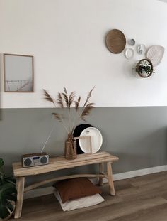 a wooden bench sitting in front of a wall with plates and plants on top of it