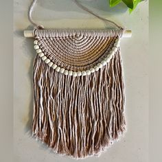 a woven purse hanging on a wall next to a plant