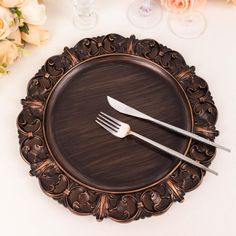 a plate with two forks and a knife on it next to some flowers in vases