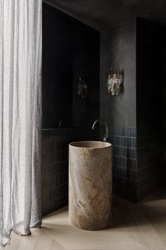 a bathroom with black walls and white marble sink in the center, along with two chandeliers