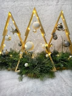 three wooden christmas trees with lights and ornaments on the top one is decorated in gold, white and silver