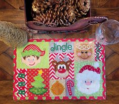 a christmas themed placemat and pine cones on a table