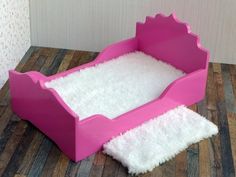 a pink dog bed with white fur on the floor