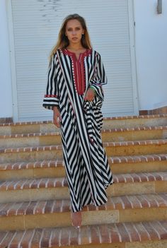 "This beautiful striped long caftan with a dash of red embroidery is a touch of class and elegance to your wardrobe. Made of breezy and light fabric, this Kaftan is ideal to wear for any casual occasion. Whether taking a trip down the shopping lane, or home-based kitty parties, or about anything else, wearing this dress will make you feel classy and comfortable. This Kaftan is ideal to wear for any casual occasion. Whether taking a trip down the shopping lane, or home-based kitty parties, or abo Traditional Tunic Abaya For Beach, Traditional Maxi Dress For Beach Eid, Traditional Maxi Dress For Eid Beach Outing, Traditional Maxi Dress For Eid Beach Occasion, Traditional Eid Maxi Dress For Beach, Black Kaftan For Beach And Eid, Traditional Kaftan For Festive Vacation, Traditional Festive Kaftan For Vacation, Traditional Floor-length Thobe For Beach