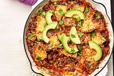 a pizza with meat, cheese and avocado on it sitting in a pan