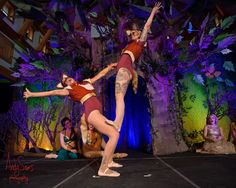 two women in red and white outfits are dancing on stage with other people behind them