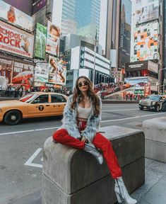 a woman sitting on top of a cement block in the middle of a city street