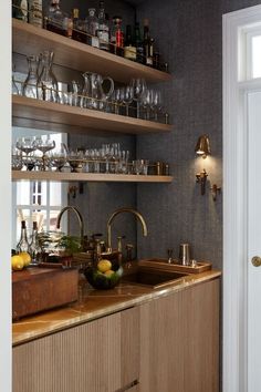 a kitchen filled with lots of counter top space and shelves full of bottles, glasses, and other items