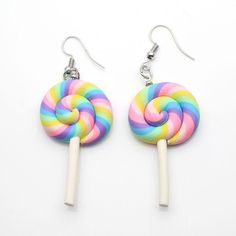 two candy lollipops are hanging from white earwires on a white background