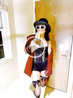 a woman in fishnet stockings and boots is drinking from a bottle while standing next to a door