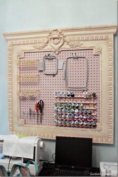 a laptop computer sitting on top of a desk next to a pegboard with magnets