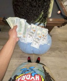 a woman sitting on the floor with money in her lap and bill sticking out of her jeans