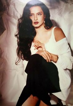 an old photo of a woman in white shirt and black skirt sitting on the floor