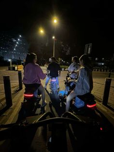 three people are riding motorcycles at night on the street with their backs turned to the camera