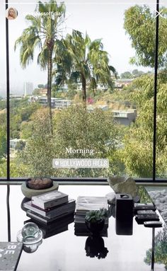 a table with books and other items on it in front of a window overlooking the city