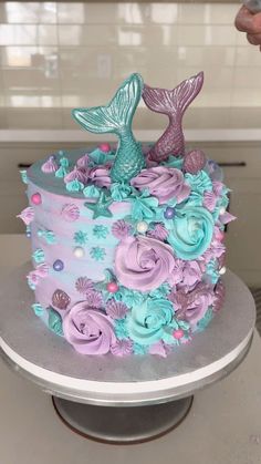 there is a cake decorated with blue and purple flowers on the top, and a mermaid tail