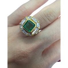 a woman's hand with an emerald and diamond ring