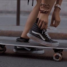 a person standing on top of a skateboard with their foot on the board and wearing bracelets