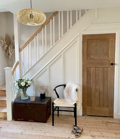 a chair sitting in front of a wooden door next to a stair case with a potted plant on it