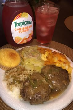 a white plate topped with meat, rice and veggies next to a drink