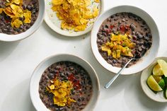 three bowls filled with black beans and tortilla chips on top of a white table