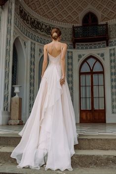 a woman in a wedding dress standing on some steps with her back to the camera