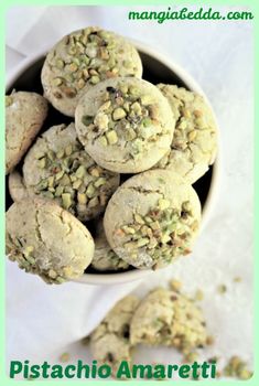 a white bowl filled with cookies covered in pistachio