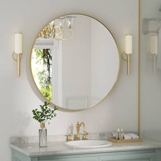 a bathroom vanity with a round mirror above it and a vase on the counter top