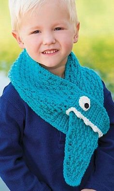 a young boy wearing a knitted scarf with an eyeball on the front and bottom