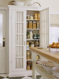 an open cabinet in the middle of a kitchen with lots of food on top of it