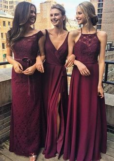 three beautiful women standing next to each other in long dresses on a bridge over looking the city