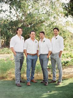 a group of men standing next to each other on top of a lush green field