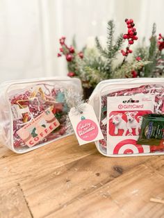 two plastic containers filled with christmas treats on top of a wooden table next to a potted plant