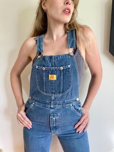 Howick vintage 1980s overalls with zipper pockets on the bottom. Marked as a size 4, these denim overalls are a straight leg cut. They have metal buttons on the sides and on the straps for the classic overall closure. There are many pockets, but take note that the denim doesn't have much stretch. Model wears size 6 and these were snug, but the length was good (model being 5'7'').  Measurements while laying flat are... waist: 14'', hip: 19'', length: 34.5". Vintage Dark Wash Denim Jumpsuit With Straight Leg, Retro Straight Leg Overalls With Pockets, Retro Denim Jumpsuit With Bib Front, Vintage Medium Wash Straight Leg Denim Jumpsuit, Vintage Bib Front Denim Jumpsuit In Medium Wash, Vintage Medium Wash Denim Jumpsuit With Bib Front, Vintage Denim Overalls In Medium Wash, Vintage Fitted Overalls In Medium Wash, Vintage Fitted Shortalls With Pockets