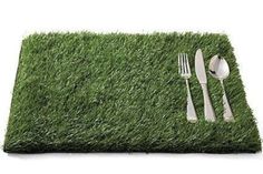 a place mat with forks and spoons on top of it, in the grass