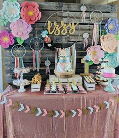 the dessert table is decorated with paper flowers and other things to eat on top of it