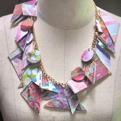 a close up of a mannequin wearing a necklace with many pieces of paper on it