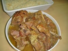 a white bowl filled with meat and vegetables next to a casserole dish on a table