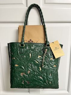 Brand New With Tag Comes with Dust Bag and Card Also comes with shoulder strap that you can use with or without Retails for $269.00 + tax so getting a great deal here Elevate your fashion game with this stunning Patricia Nash Adeline shoulder bag. Crafted from high-quality tooled leather in a  green hue, this bag is perfect for a stylish woman who wants to make a statement. The intricate cut-out accents add a touch of uniqueness to the bag, making it stand out in any crowd. The spacious interior and sturdy shoulder strap make this bag perfect for everyday use. Whether you're heading to work or running errands, the Patricia Nash Adeline tote shoulder bag is the perfect accessory to complete your outfit. Add it to your collection today! Style: Adeline Magnetic snap closure, cutout leather to Luxury Green Bag With Interior Card Slots, Green Crossbody Bag With Interior Card Slots, Leather Shoulder Bag With Interior Card Slots For Errands, Crossbody Shoulder Bag With Interior Card Slots For Shopping, Tooled Leather, Leather Tooling, Leather Handle, Smooth Leather, Running Errands