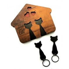 two cats are standing in front of a house shaped keychain that has been cut out