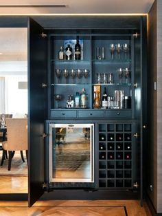 a black cabinet with wine glasses and bottles on it's doors is open to the dining room