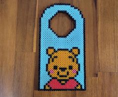 a bottle opener made out of perler beads on a wooden floor with a cartoon character